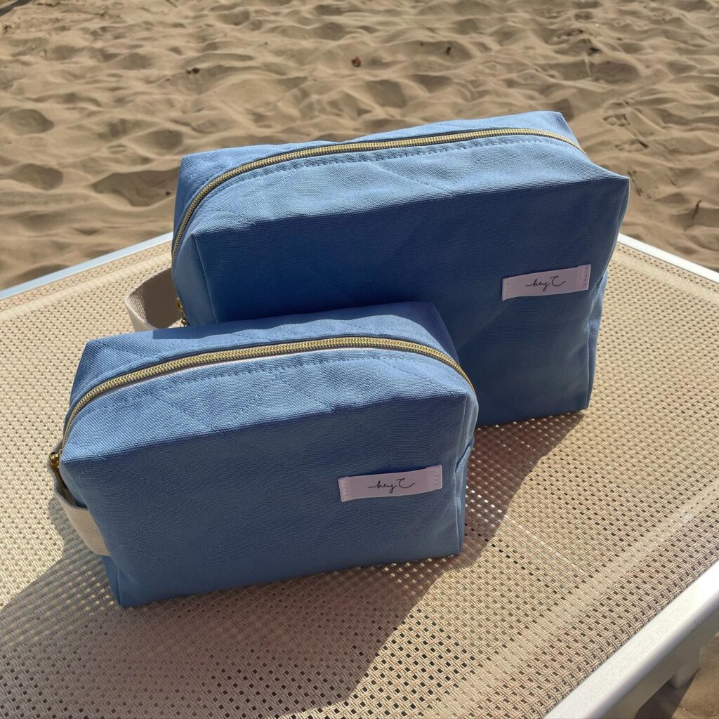 Zwei Kosmetiktaschen in Hellblau auf einer Sonnenliege am Strand