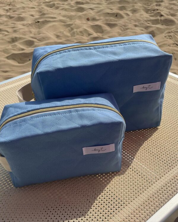 Zwei Kosmetiktaschen in Hellblau auf einer Sonnenliege am Strand