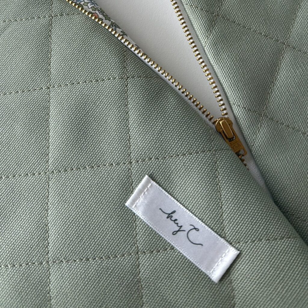 Detail: gesteppter Stoff in Salbeigrün mit Reißverschluss und hey C Label