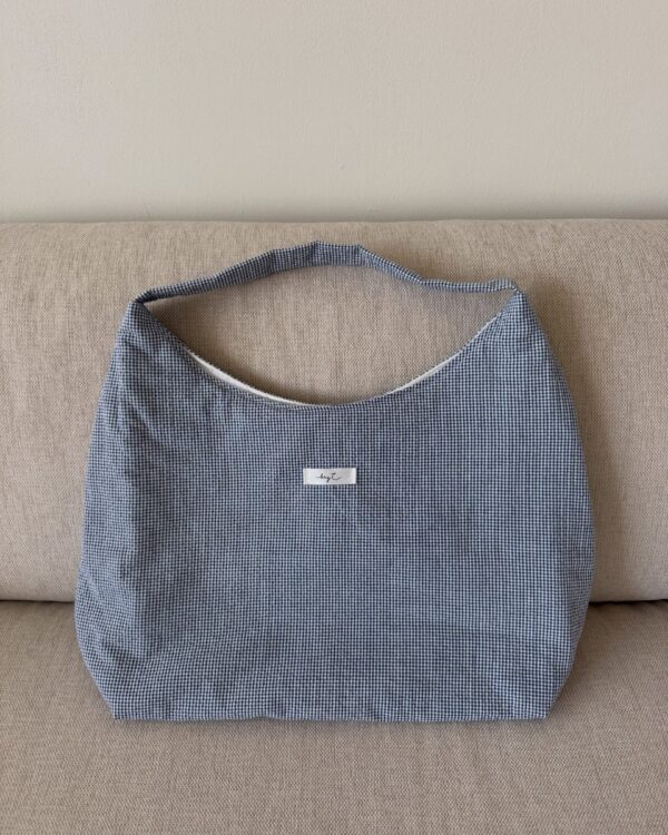 Maxi Summer Bag aus blau-weiß kariertem Stoff auf einem Sofa