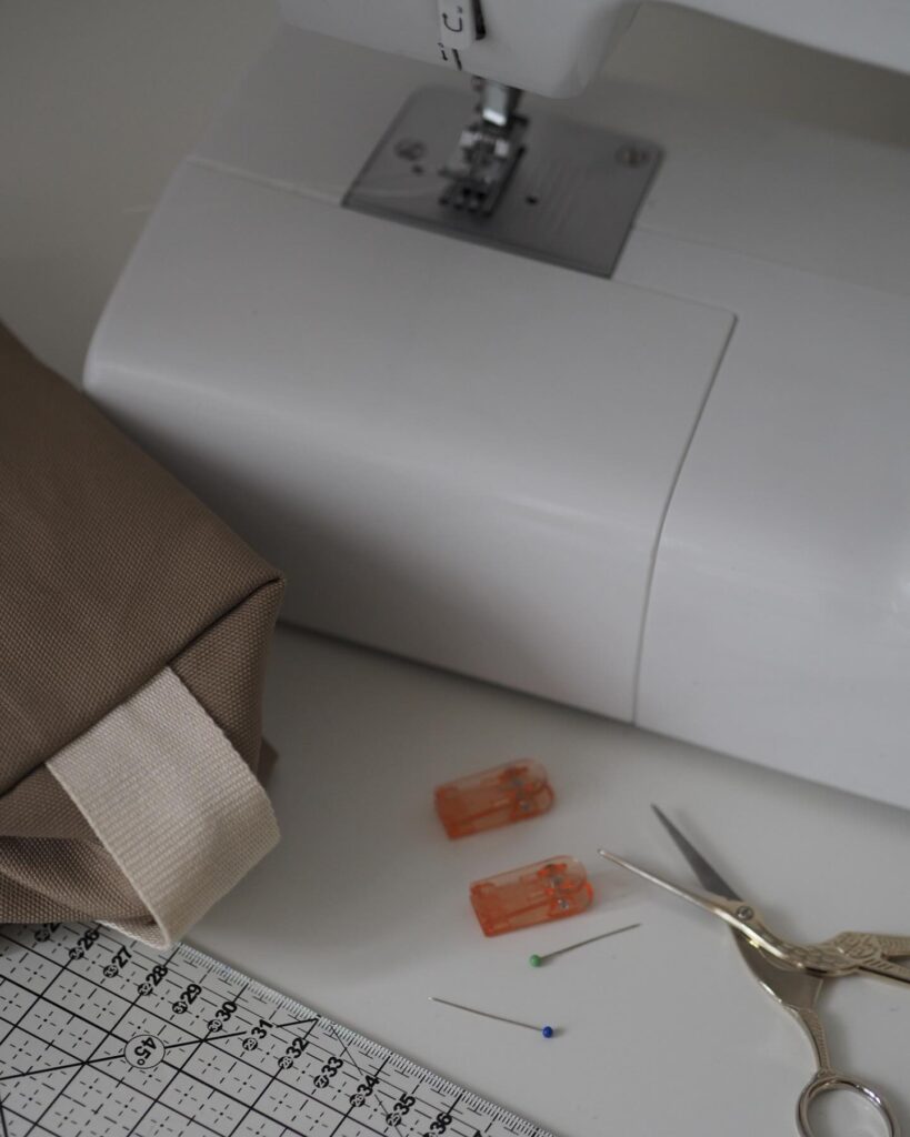 Nähmaschine mit Stoff, Schere und Stecknadeln