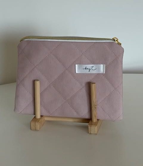 Gesteppte Pouch in Light Pink mit goldenem Rei&szlig;verschluss auf einem Holzst&auml;nder